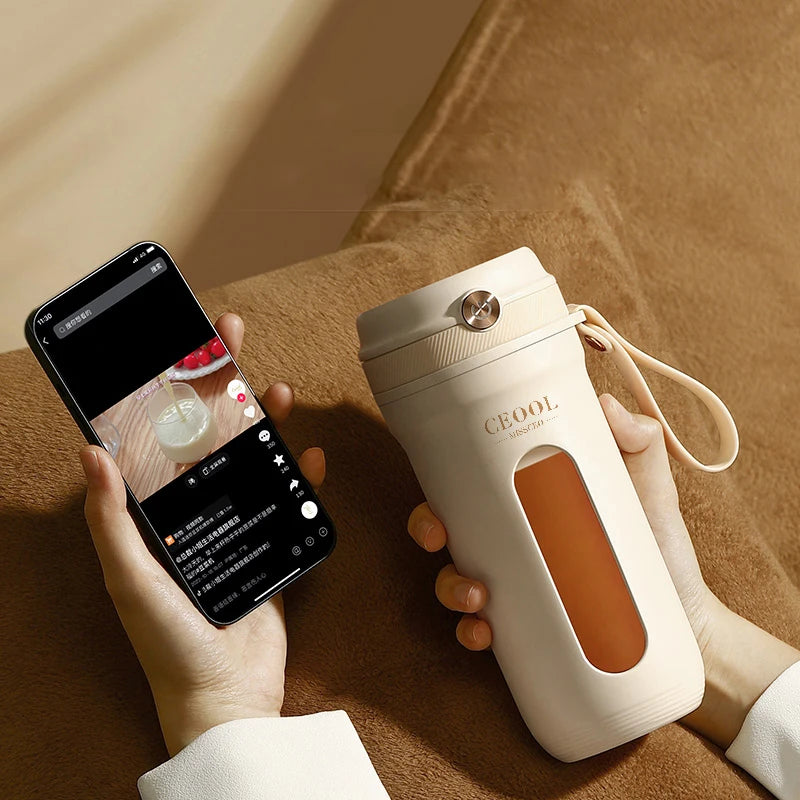 Person holding a white thermos with a brown interior and a smartphone on a wooden surface.